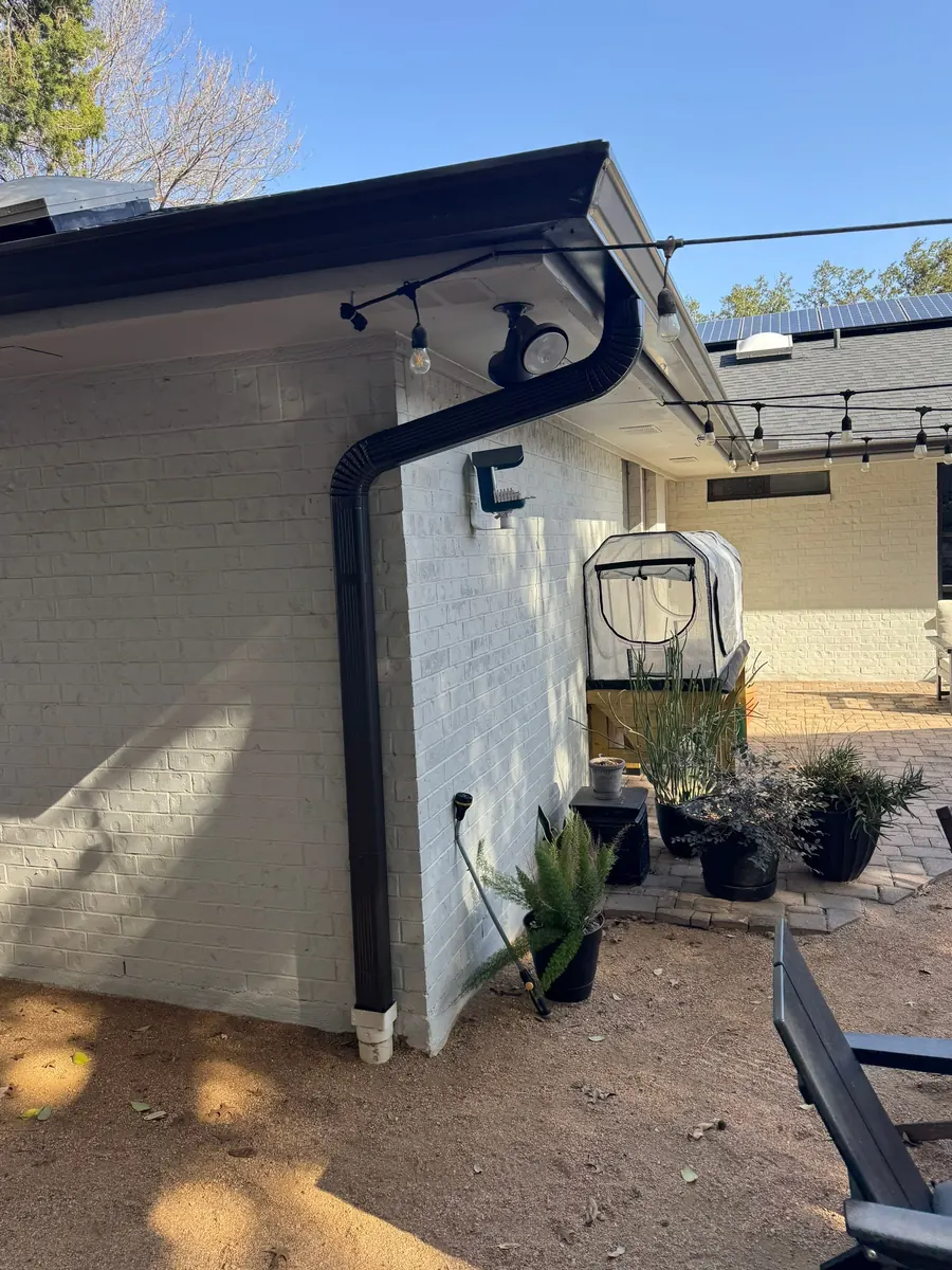 Black gutter and downspout on a white painted-brick house