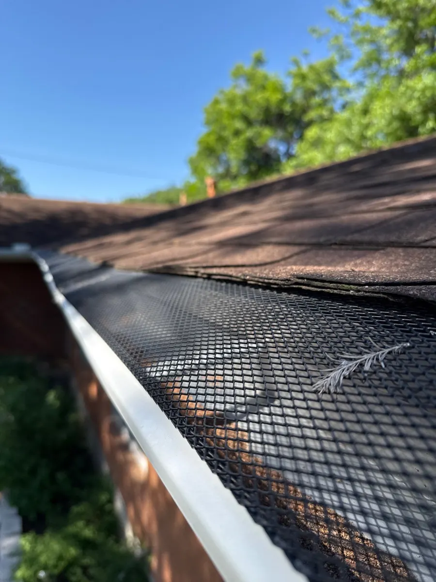 Black mesh gutter guard over a white gutter
