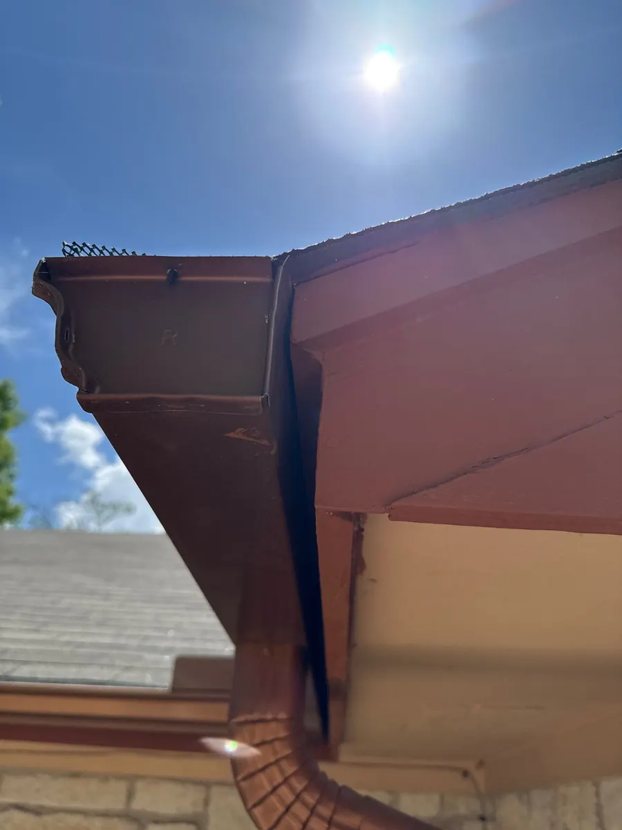 Brown gutter and downspout at a soffit corner