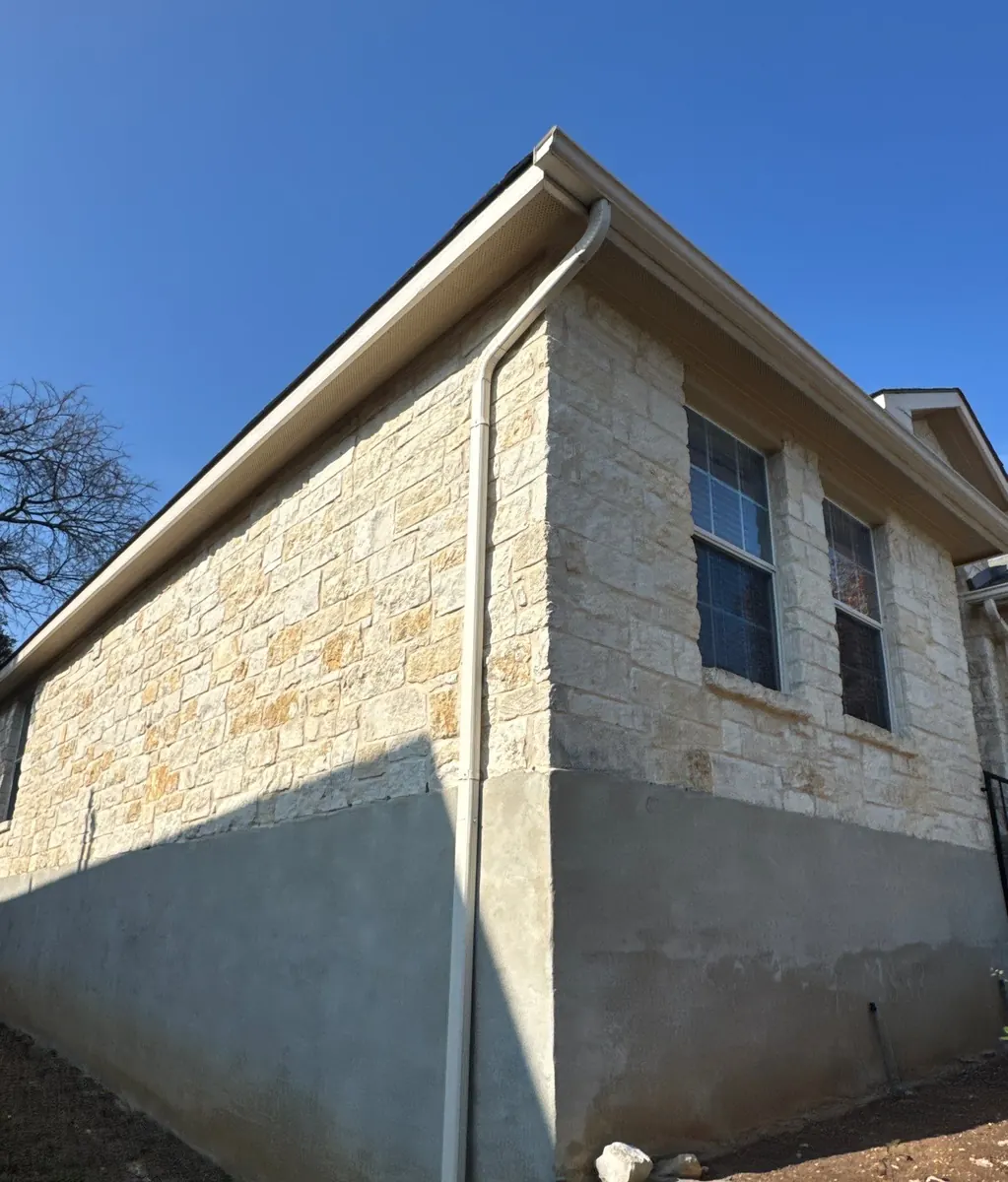 White downspout on the corner of a limestone house