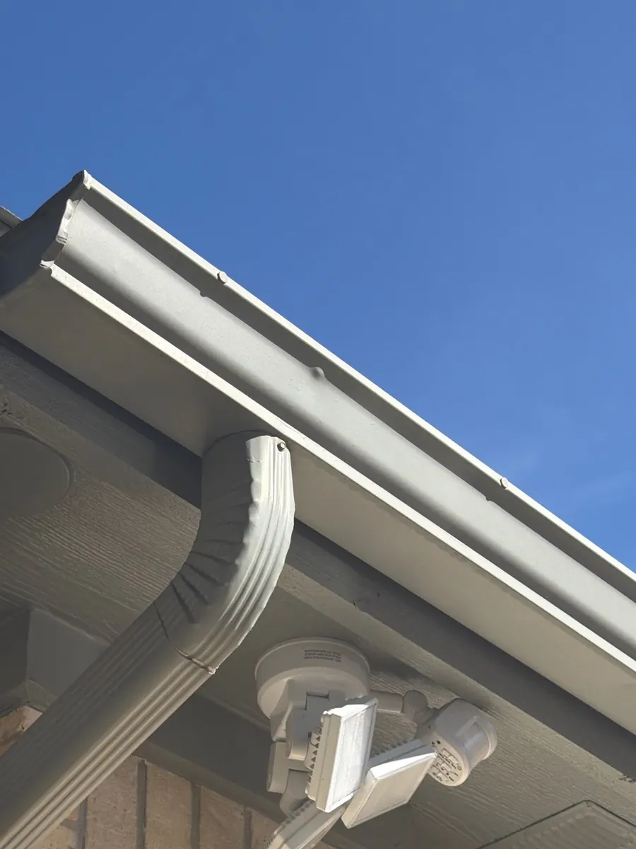 White gutter corner with a downspout and elbow